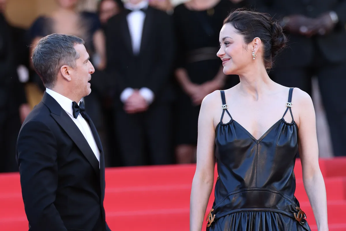 Guillaume Canet and Marion Cotillard smiling and posing together at a press conference.