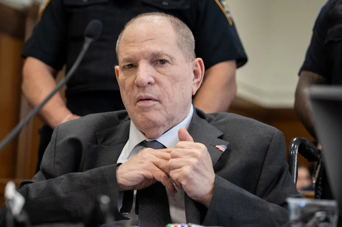 A somber-looking Harvey Weinstein walking into a courthouse.