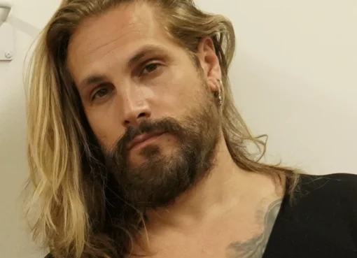 Marco Perego, fresh and smiling, sitting at a cafe table with a coffee cup, possibly at the Majestic hotel on the Croisette in Cannes.