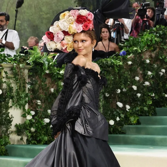 Zendaya striking a pose on the red carpet at the Met Gala in a stunning, dramatic gown.