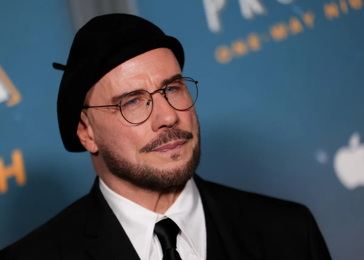 John Travolta smiling and wearing a stylish beret.