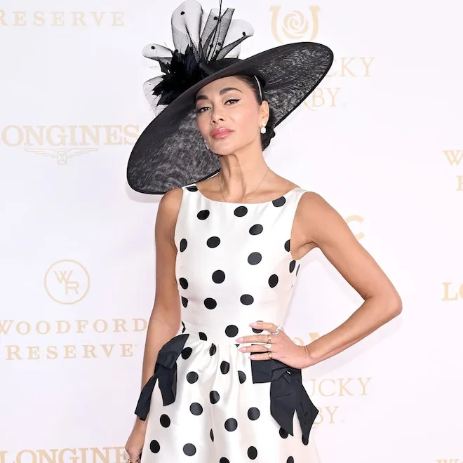 Nicole Scherzinger smiling at the Kentucky Derby, wearing a large, stylish hat and a colorful dress.