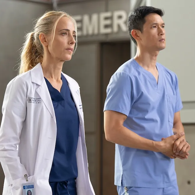 Doctors in scrubs looking concerned in a hospital hallway.