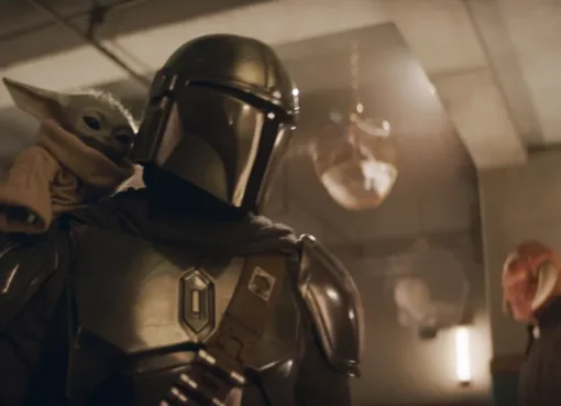 The Mandalorian and Grogu standing in a desert landscape with a spaceship in the background.