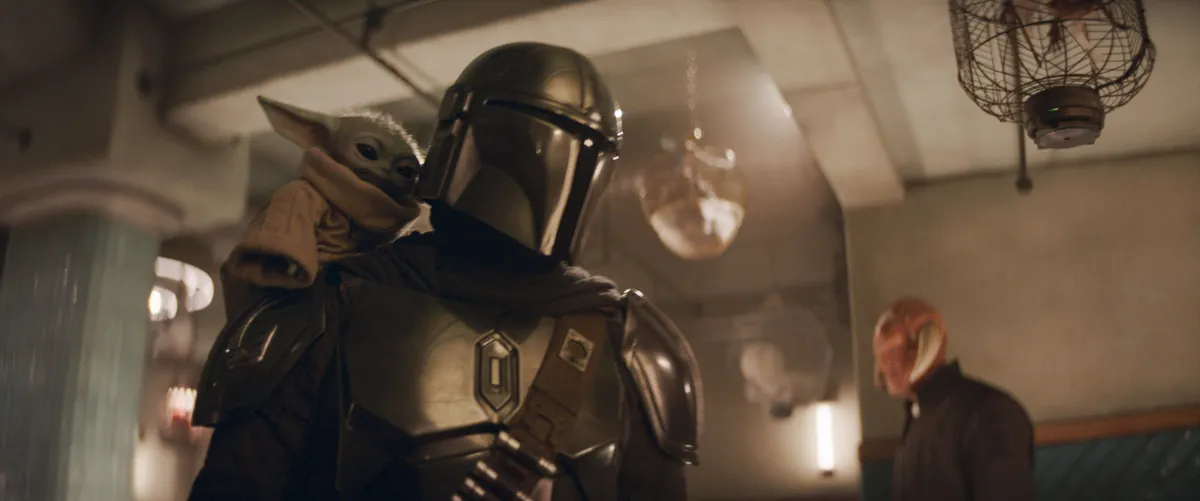 The Mandalorian and Grogu standing in a desert landscape with a spaceship in the background.