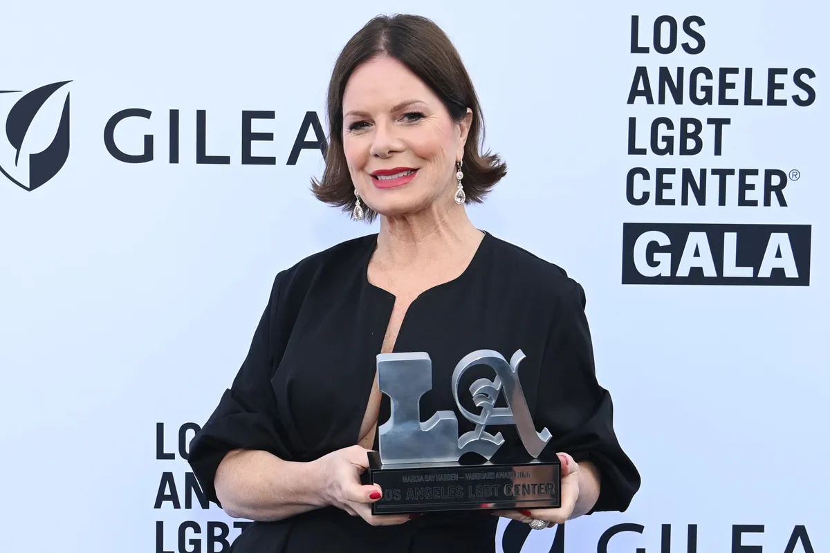 Marcia Gay Harden speaking at a colorful gala event