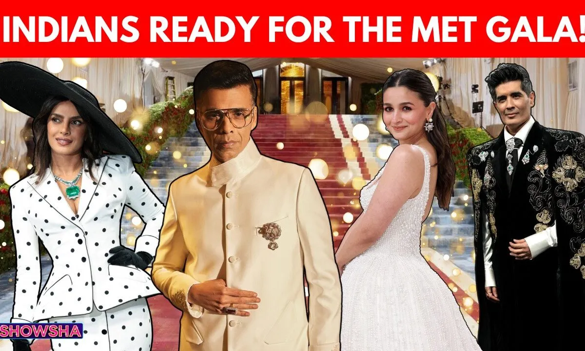 Karan Johar smiling, wearing a stylish, possibly maximalist outfit, with Met Gala branding subtly in the background.