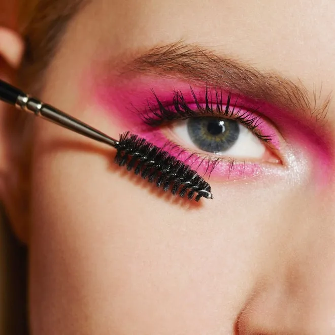 A colorful flat lay of various makeup, skincare, and haircare products like serums, lipsticks, and brushes, with a 'Sale' tag visible.