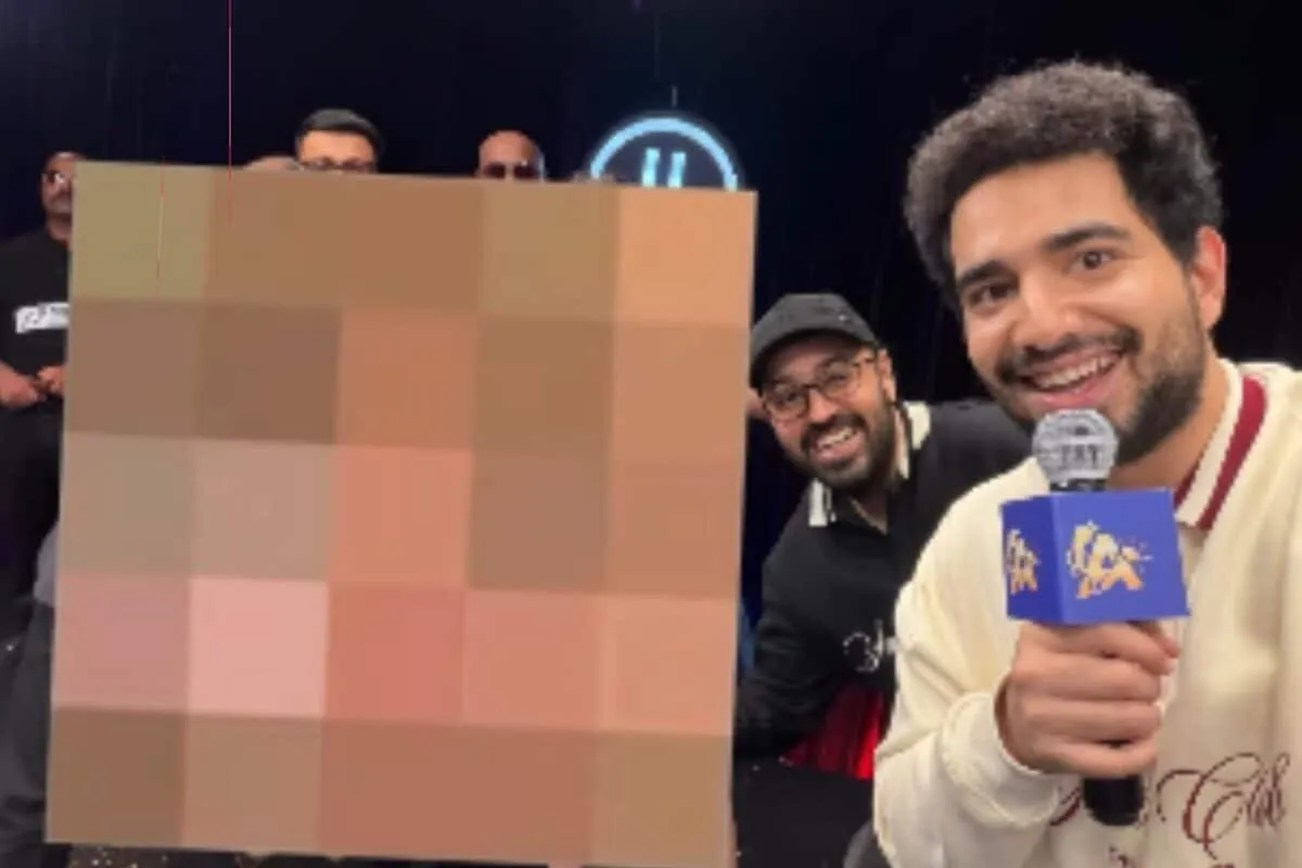 Samay Raina on the set of a show, looking at his phone.