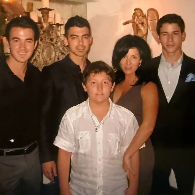The Jonas Brothers smiling and looking like they're sharing gift ideas.