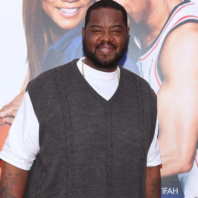 Grizz Chapman smiling slightly, possibly in character as a bodyguard.