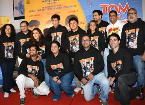 Paritosh Painter smiling at the premiere of his new film, TOM AND JERRY, with a vibrant movie poster in the background.