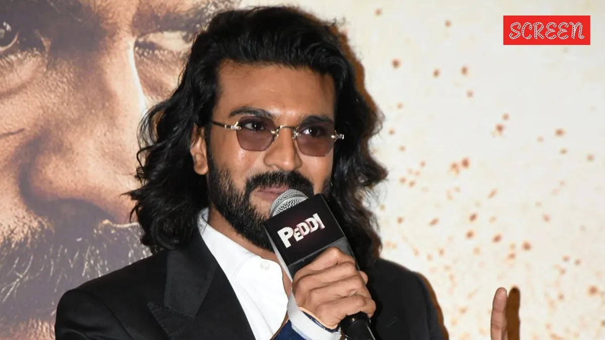 Ram Charan smiling, possibly at a film event.