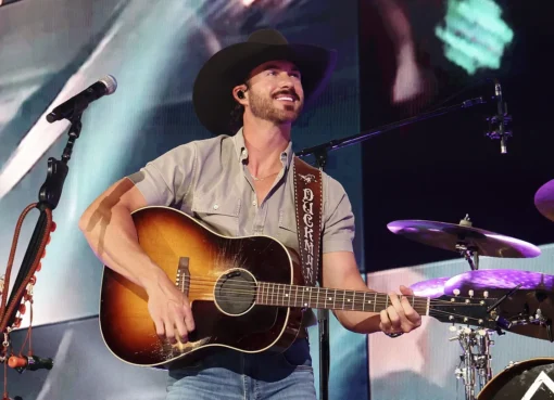 Riley Green smiling and performing on stage.