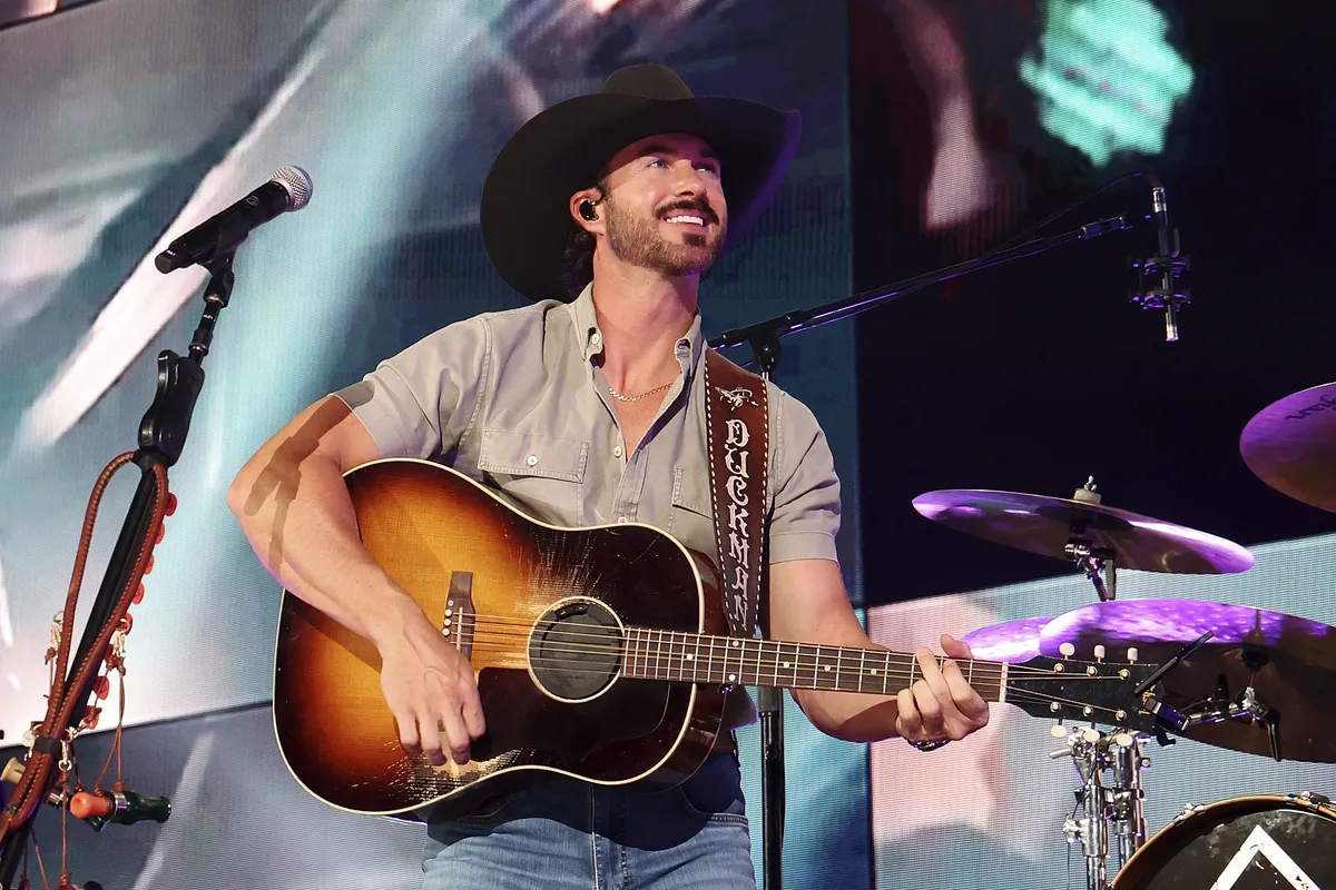 Riley Green smiling and performing on stage.