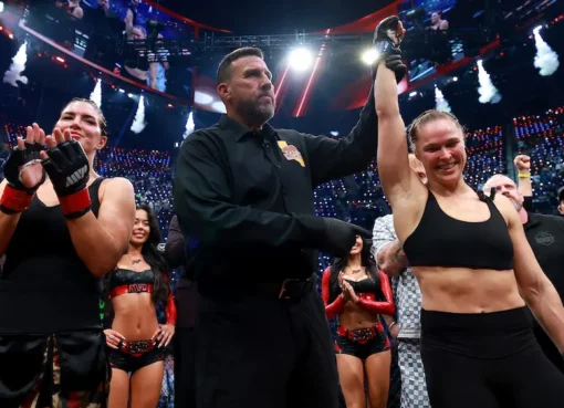 Ronda Rousey and Gina Carano facing off in a brightly lit fighting ring