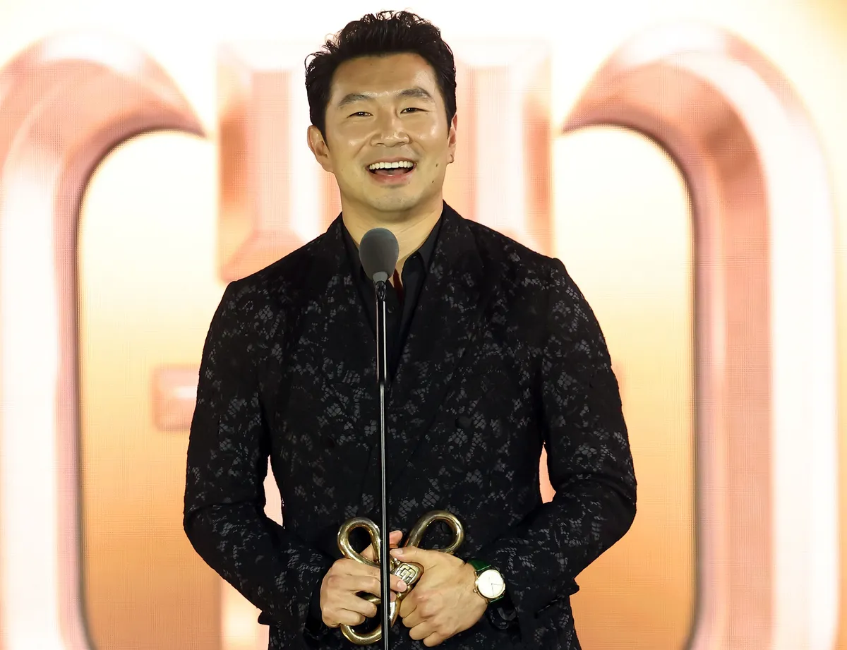 Simu Liu accepting an award on stage.