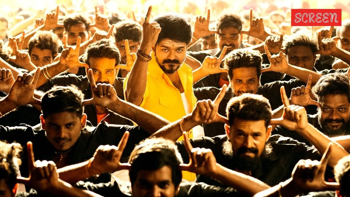 Crowds cheering excitedly at a movie theater, celebrating Vijay's election win.