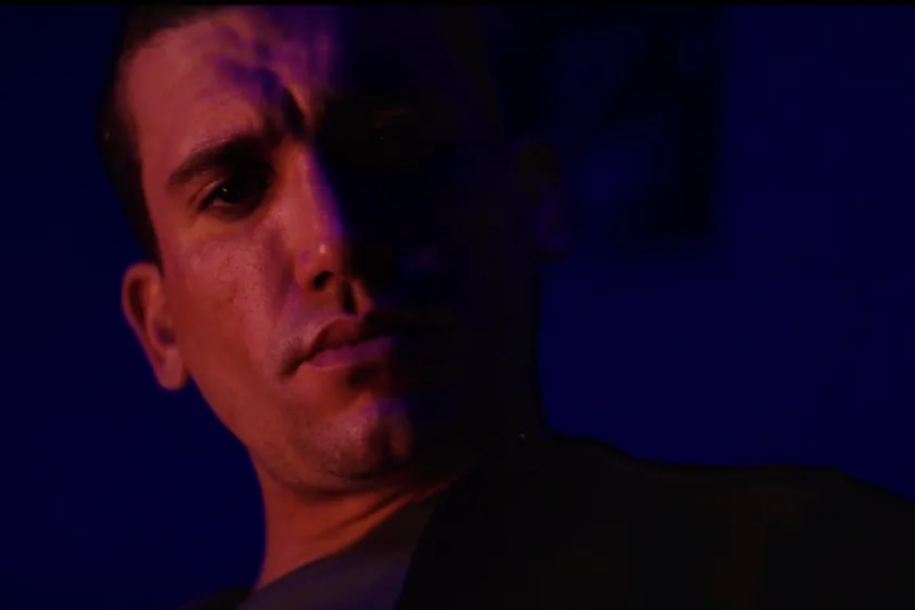 Jaime Lorente looking intense and serious in a dimly lit scene, possibly from a horror film.