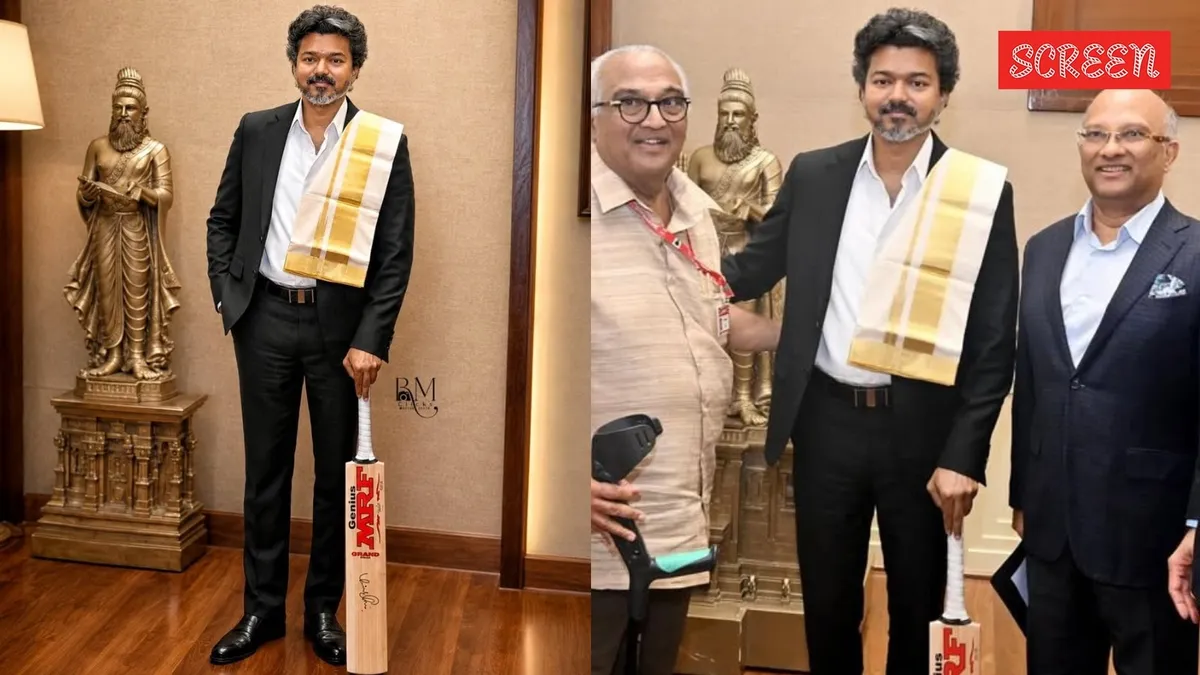 Tamil Nadu CM holding a red and gold cricket bat signed by Virat Kohli.