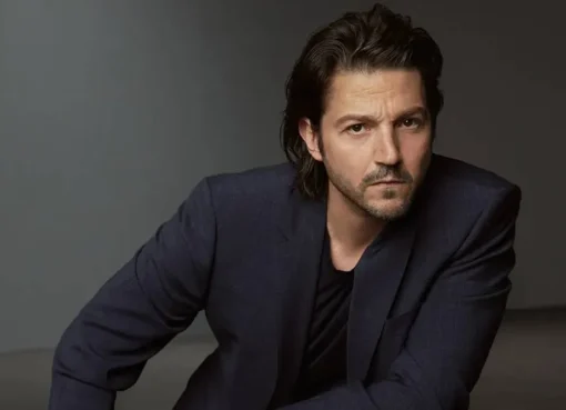 Diego Luna smiling, against a background hinting at the whimsical, magical world of Tangled with glowing lanterns.