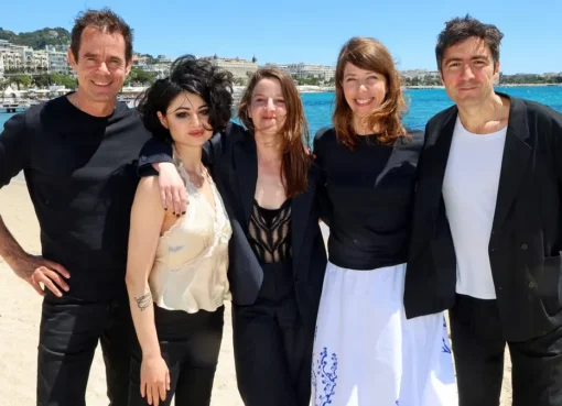 Five filmmakers smiling and posing together at a press conference.