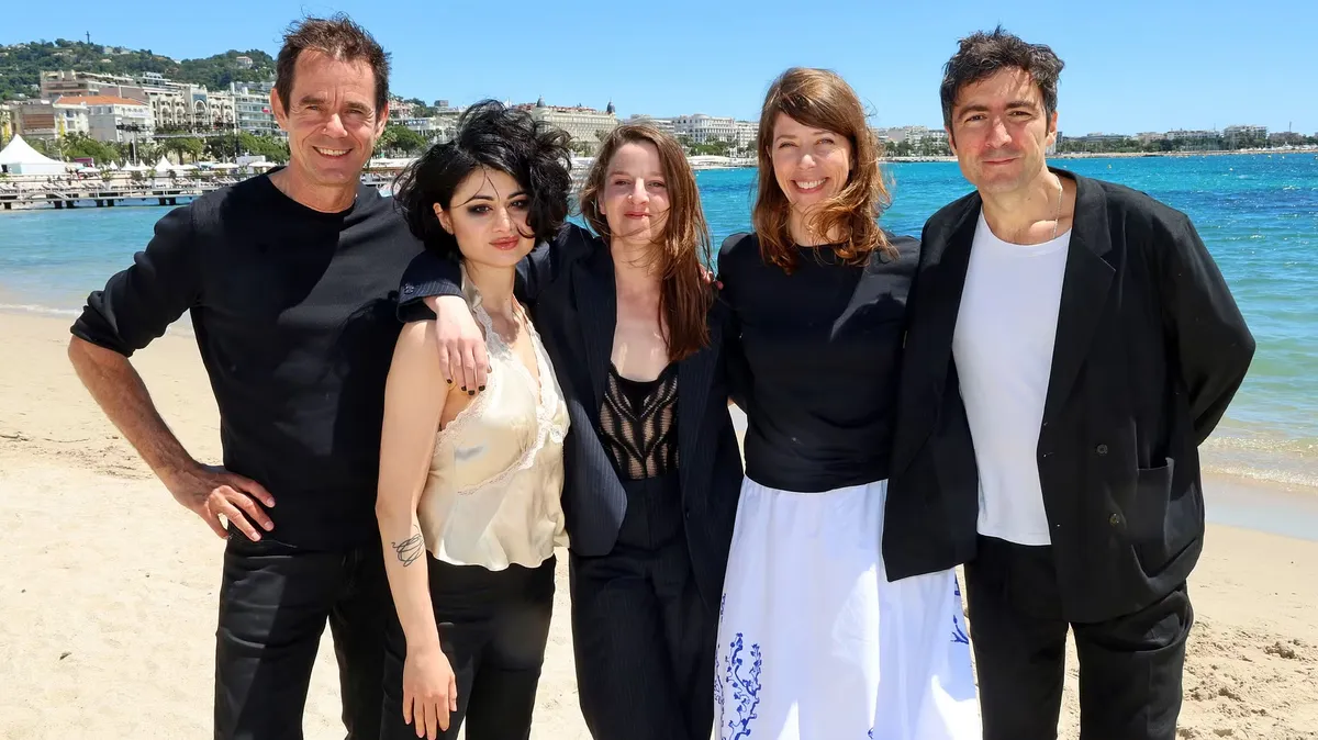 Five filmmakers smiling and posing together at a press conference.