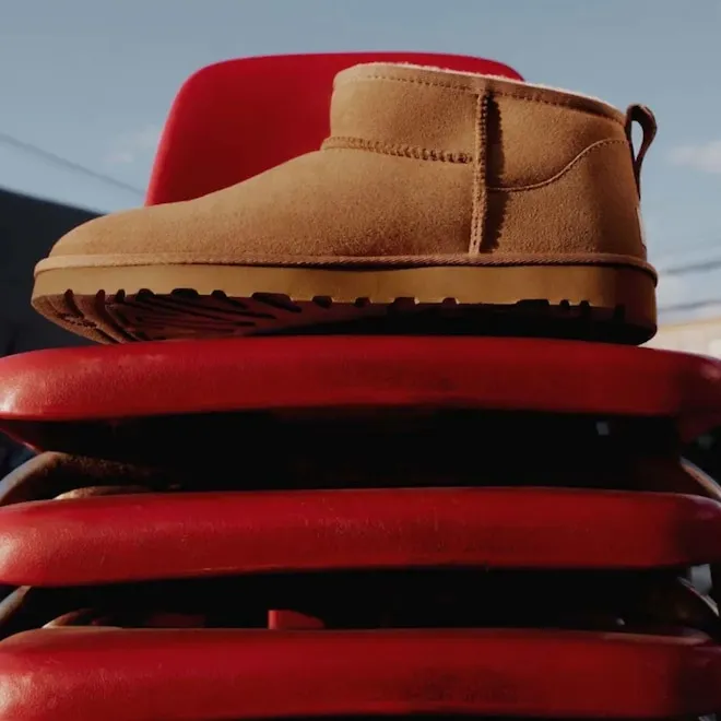 A close-up shot of several cozy UGG slippers and boots in various warm, earthy colors.