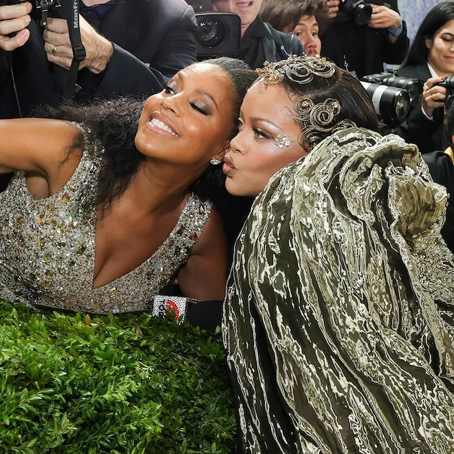 Rihanna smiling and talking to Sheinelle Jones on the Met Gala red carpet.