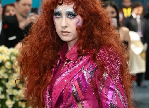 Chappell Roan at the Met Gala in a colorful patchwork suit and feathered cape.
