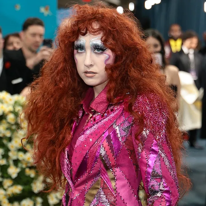 Chappell Roan at the Met Gala in a colorful patchwork suit and feathered cape.