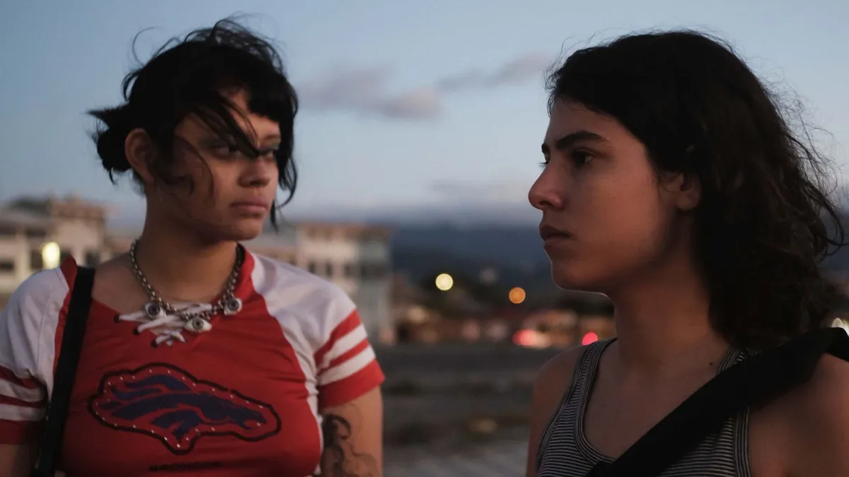 Two young women, sisters, sitting across from each other at a mall restaurant table.