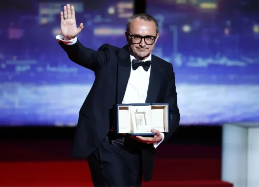Andrey Zvyagintsev on stage at the Cannes Film Festival, holding an award and speaking into a microphone.
