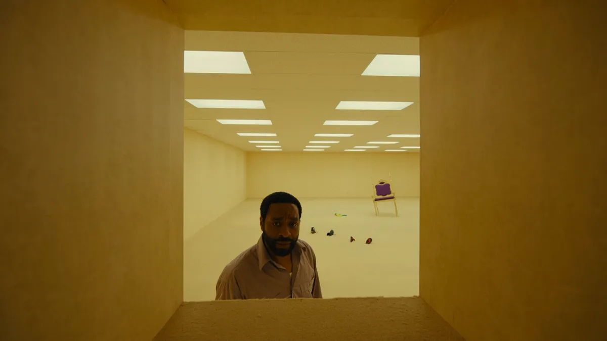 A still from the 'Backrooms' movie, showing an unsettling, endless hallway with yellow walls and fluorescent lights.