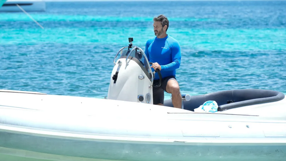 A yacht sailing on a bright blue ocean.