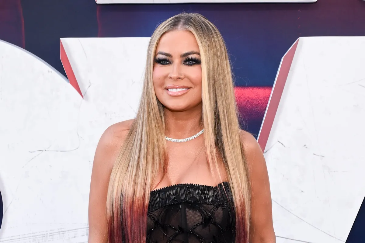 Carmen Electra smiling brightly on a red carpet.