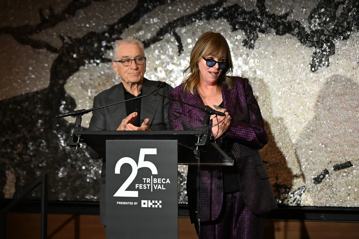 Robert De Niro speaking passionately into a microphone on stage, with a serious expression at the Tribeca Festival.