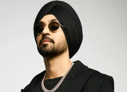 Diljit Dosanjh smiling and waving to a crowd during a performance.