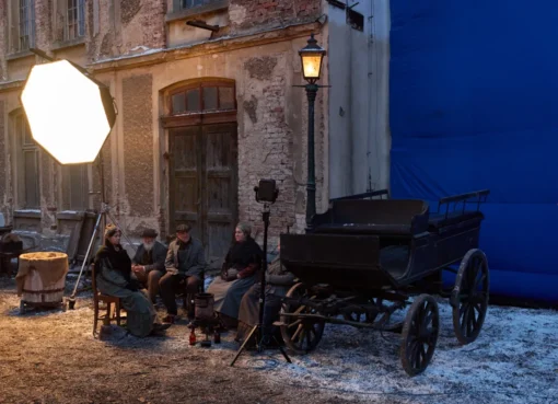 A film crew setting up cameras in a scenic European city with old buildings.
