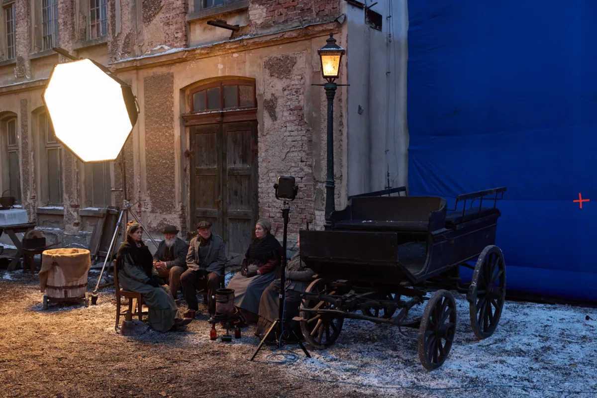 A film crew setting up cameras in a scenic European city with old buildings.