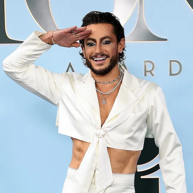 Frankie Grande smiling proudly, perhaps looking at a screen showing Ariana Grande.