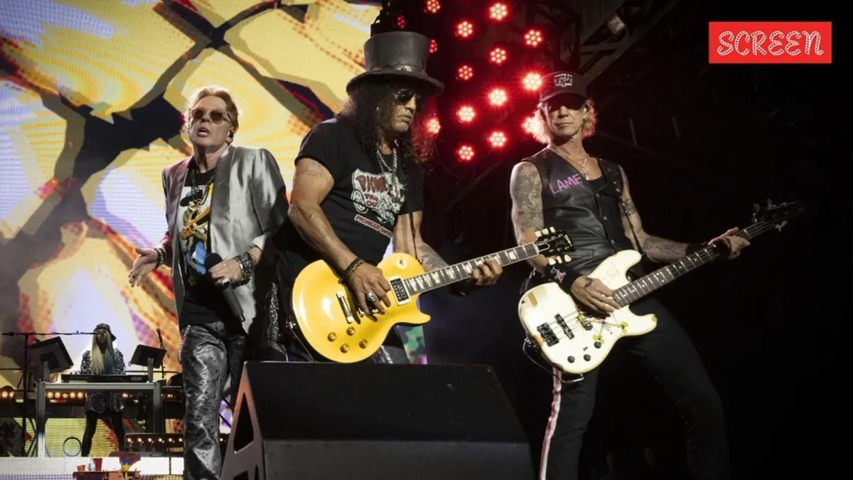 Guns N' Roses band members performing on stage with vibrant lighting.
