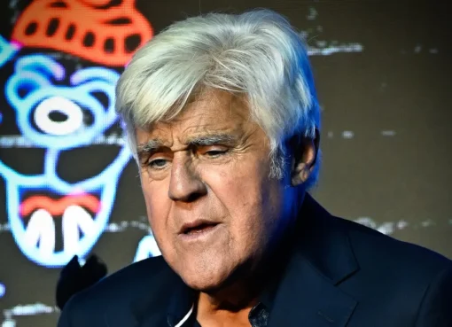 Jay Leno smiling on a talk show set with bright lights