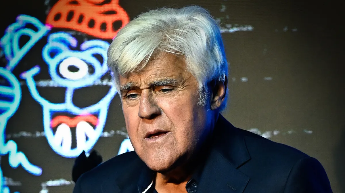 Jay Leno smiling on a talk show set with bright lights