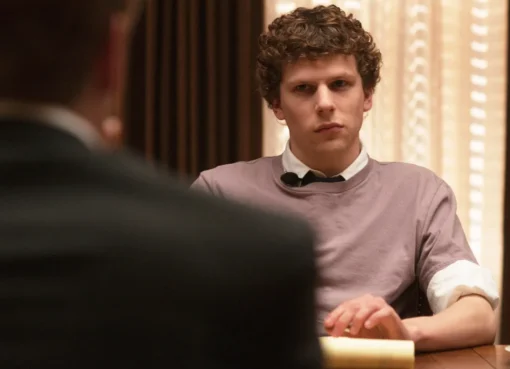 Jesse Eisenberg looks thoughtfully at the camera, wearing a casual jacket.