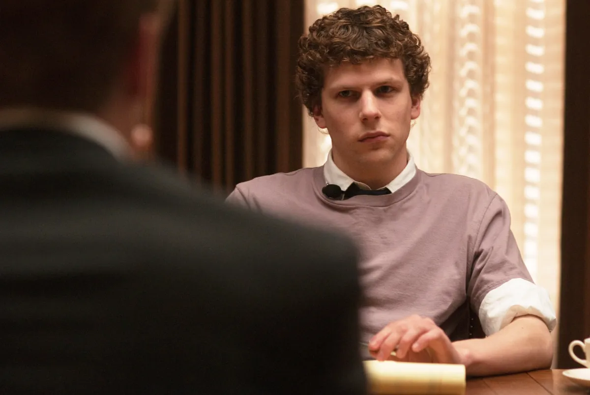 Jesse Eisenberg looks thoughtfully at the camera, wearing a casual jacket.