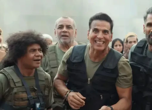 Akshay Kumar smiling in a promotional poster for "Welcome To The Jungle" with jungle-themed elements.