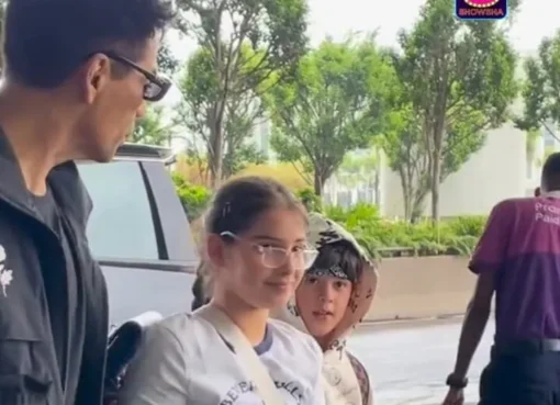 Karan Johar smiling with his children Yash and Roohi at the airport, ready for their journey.