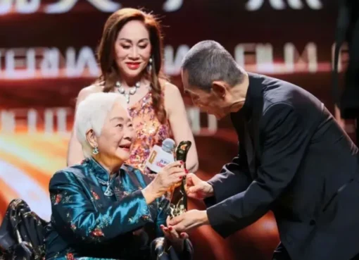 Lisa Lu smiling on stage at a film festival event.