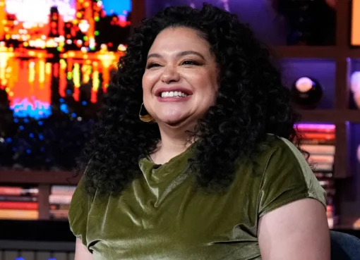 Michelle Buteau laughing and smiling during a talk show appearance.